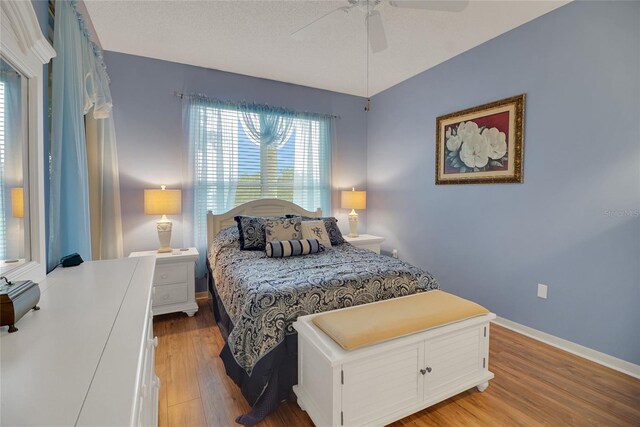 32915 Crooked Oaks Ln, Leesburg, FL 34748 - bedroom featuring light wood-type flooring, ceiling fan, a textured ceiling, and baseboards
