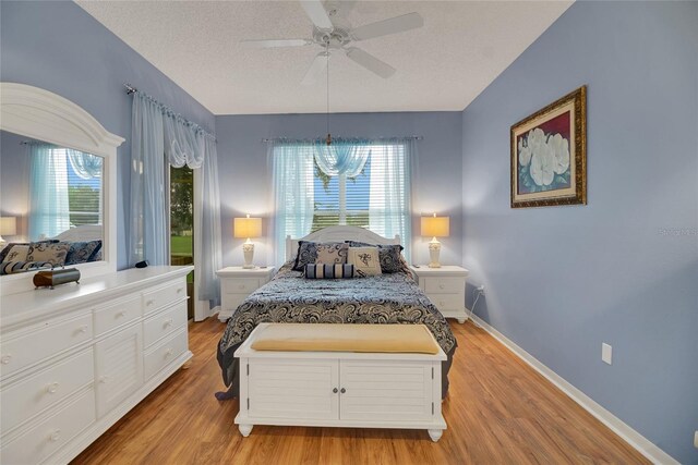 32915 Crooked Oaks Ln, Leesburg, FL 34748 - bedroom featuring baseboards, multiple windows, light wood-style flooring, and a textured ceiling