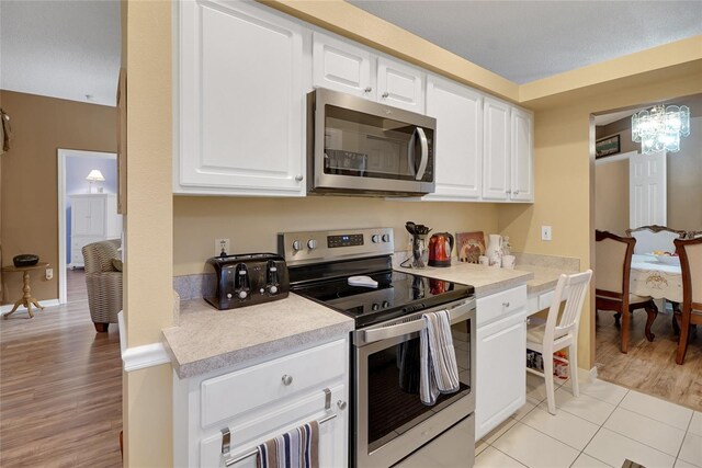 32915 Crooked Oaks Ln, Leesburg, FL 34748 - kitchen featuring light tile patterned floors, stainless steel appliances, white cabinetry, baseboards, and light countertops