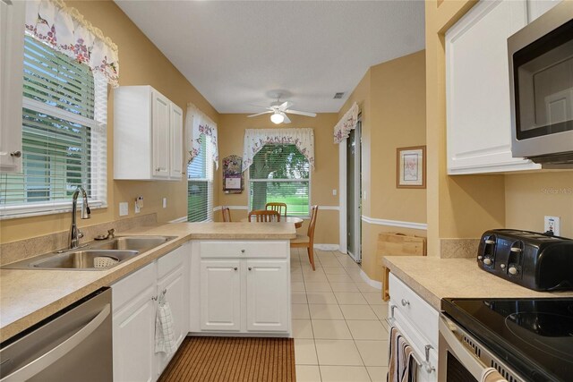 32915 Crooked Oaks Ln, Leesburg, FL 34748 - kitchen featuring light tile patterned floors, stainless steel appliances, a sink, white cabinets, and light countertops