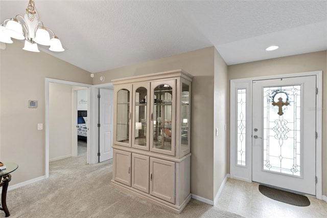 foyer entrance featuring lofted ceiling, a textured ceiling, a chandelier, and a wealth of natural light