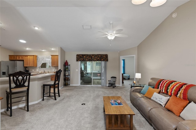 living area featuring visible vents, baseboards, a ceiling fan, light colored carpet, and vaulted ceiling