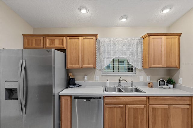 kitchen featuring a textured ceiling, appliances with stainless steel finishes, light countertops, and a sink