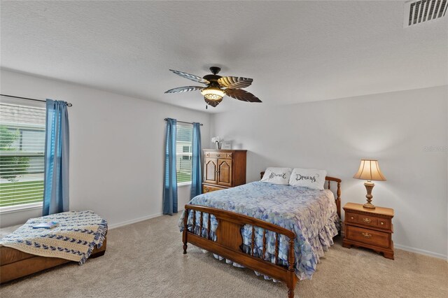 bedroom with light colored carpet, visible vents, ceiling fan, a textured ceiling, and baseboards