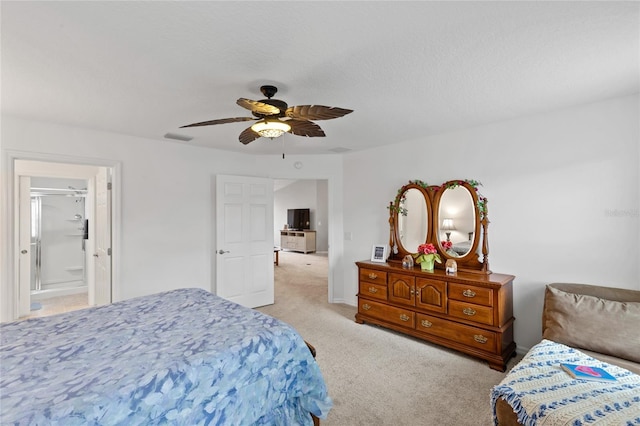 bedroom with visible vents, a ceiling fan, light colored carpet, ensuite bath, and a textured ceiling