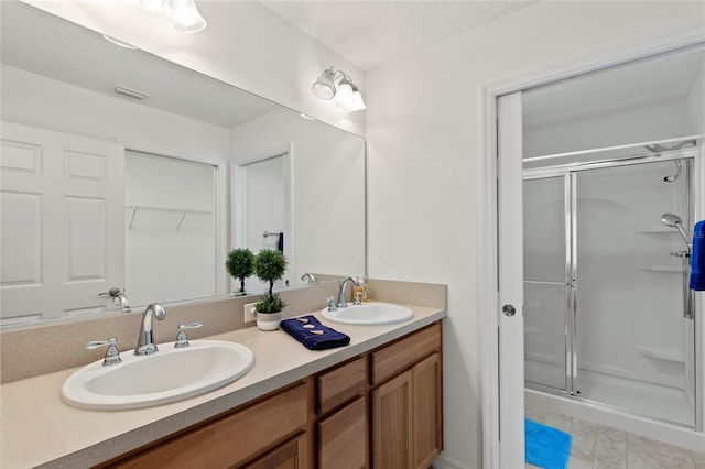 full bath featuring double vanity, a shower stall, a walk in closet, and a sink