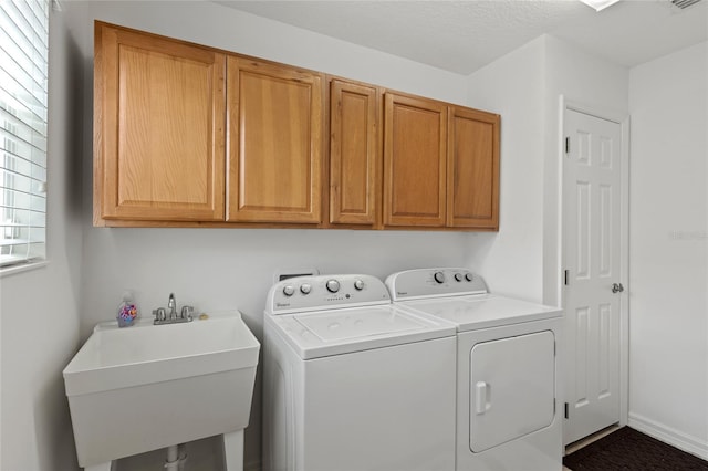 clothes washing area with a sink, visible vents, baseboards, cabinet space, and washing machine and clothes dryer