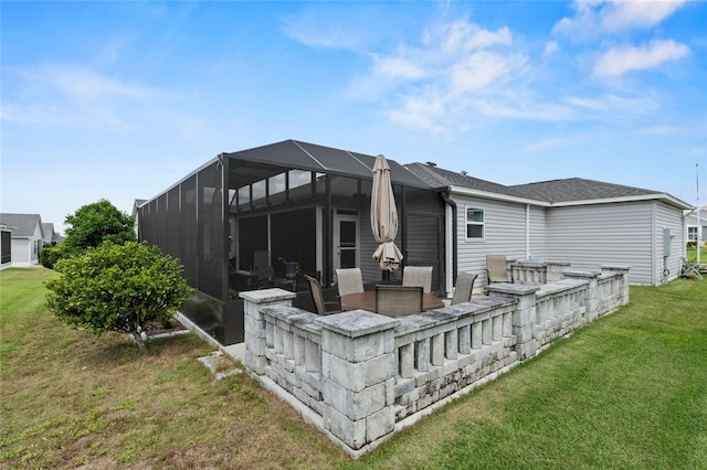 rear view of house featuring glass enclosure, a patio area, a fire pit, and a lawn