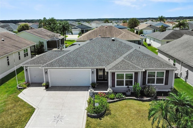 view of front of home featuring a garage, driveway, a residential view, roof with shingles, and a front yard