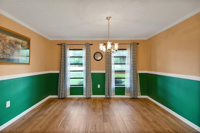 unfurnished dining area with a notable chandelier, hardwood / wood-style floors, and crown molding