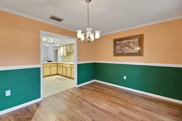 unfurnished dining area featuring light tile patterned flooring, sink, ornamental molding, and a chandelier