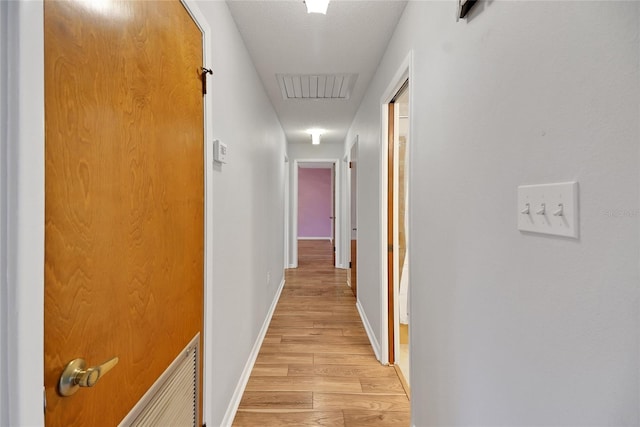 hallway with light hardwood / wood-style floors and a textured ceiling