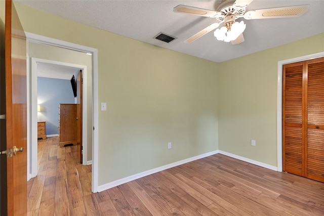 unfurnished bedroom with ceiling fan, wood-type flooring, a closet, and a textured ceiling