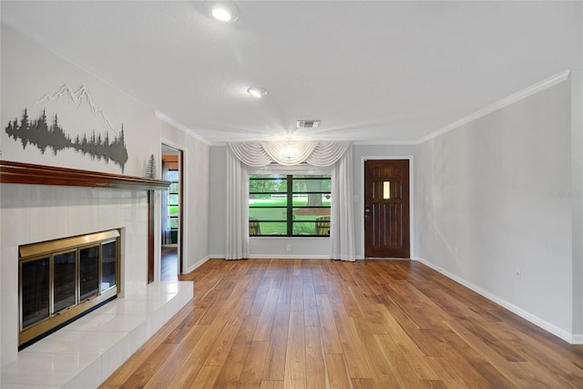 unfurnished living room with a tiled fireplace, light hardwood / wood-style flooring, and ornamental molding