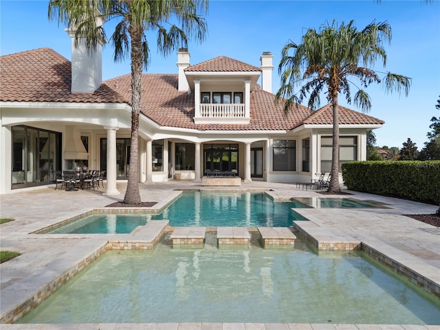 rear view of property with a patio area and a swimming pool with hot tub