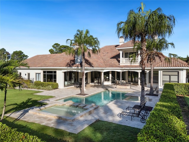 back of house with a yard, a balcony, a patio area, and a pool with hot tub