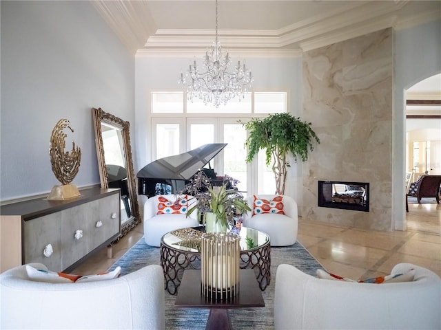 living room with a premium fireplace, crown molding, a high ceiling, and a chandelier