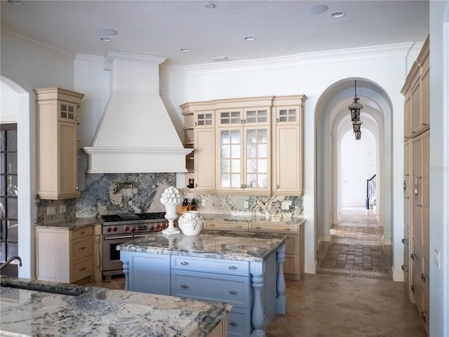 kitchen featuring premium range hood, a kitchen island, crown molding, and stainless steel stove