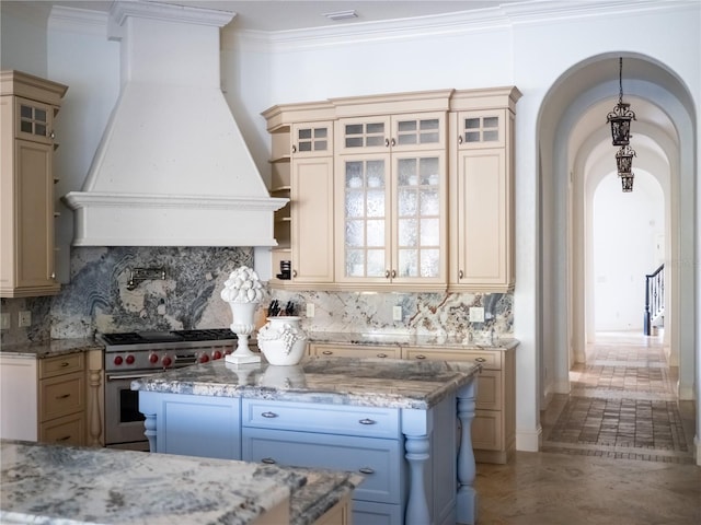 kitchen featuring a center island, light stone counters, high end stainless steel range, custom exhaust hood, and ornamental molding