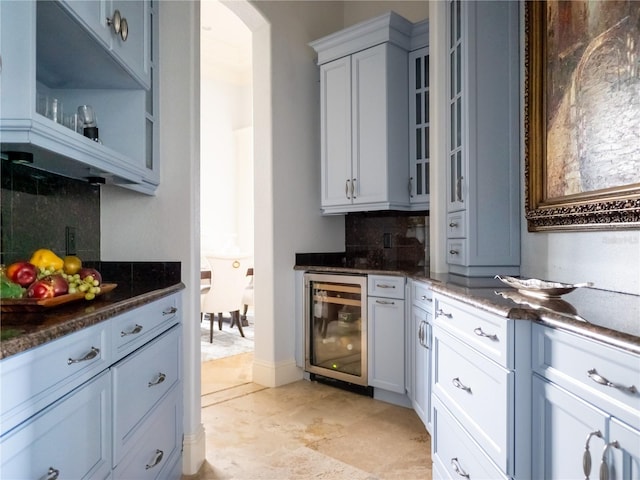 kitchen with backsplash, beverage cooler, and dark stone countertops