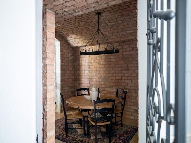 dining area with vaulted ceiling and brick wall