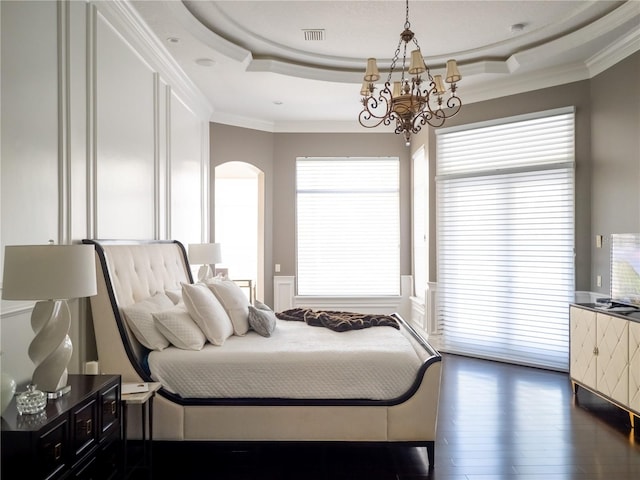 bedroom with a raised ceiling, dark hardwood / wood-style flooring, crown molding, and a notable chandelier