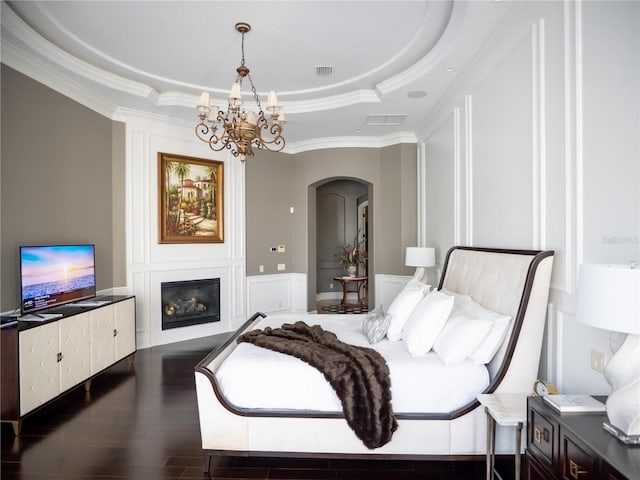 bedroom with a chandelier, dark hardwood / wood-style flooring, a raised ceiling, and ornamental molding