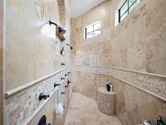 bathroom with a tile shower and tile walls