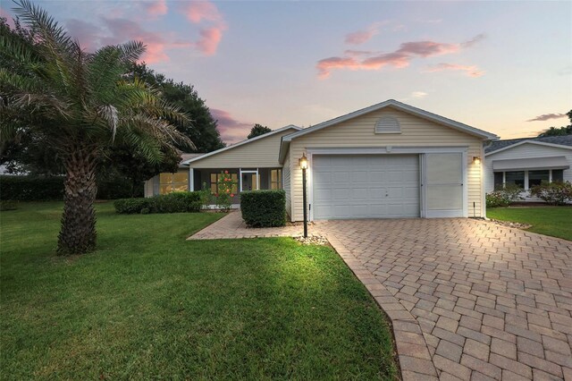 ranch-style home featuring a lawn and a garage