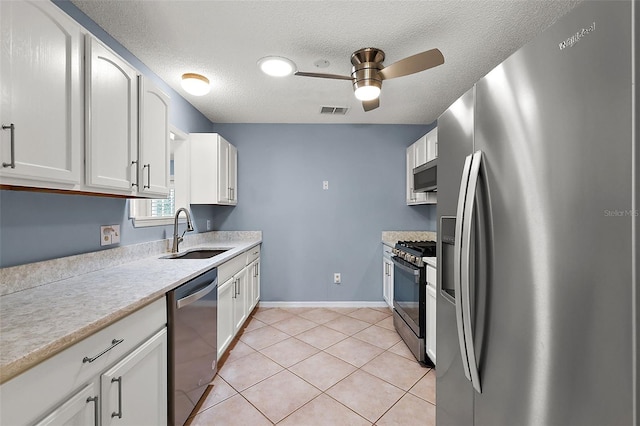 kitchen with white cabinets, appliances with stainless steel finishes, sink, light tile patterned flooring, and ceiling fan