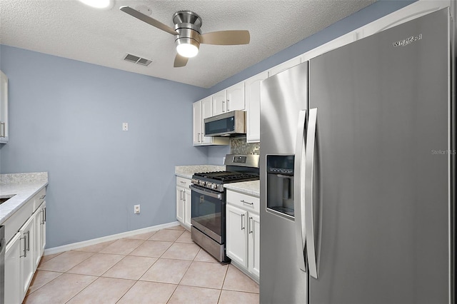 kitchen featuring white cabinetry, a textured ceiling, light tile patterned floors, ceiling fan, and appliances with stainless steel finishes