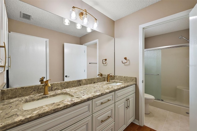 bathroom featuring toilet, tile patterned floors, a shower with door, vanity, and a textured ceiling