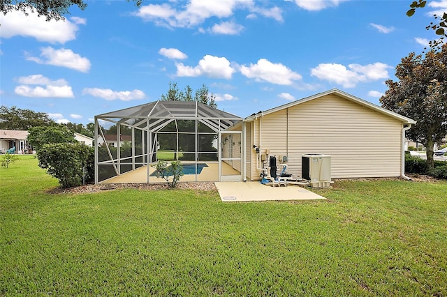 back of house with glass enclosure, central air condition unit, a yard, and a patio