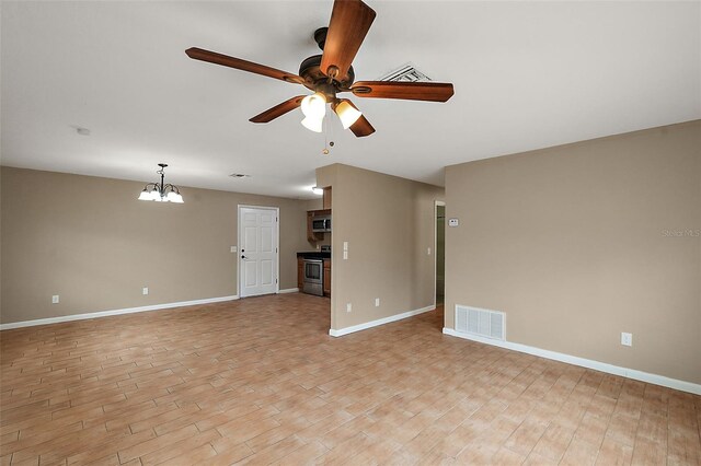 unfurnished living room with ceiling fan with notable chandelier and light hardwood / wood-style floors