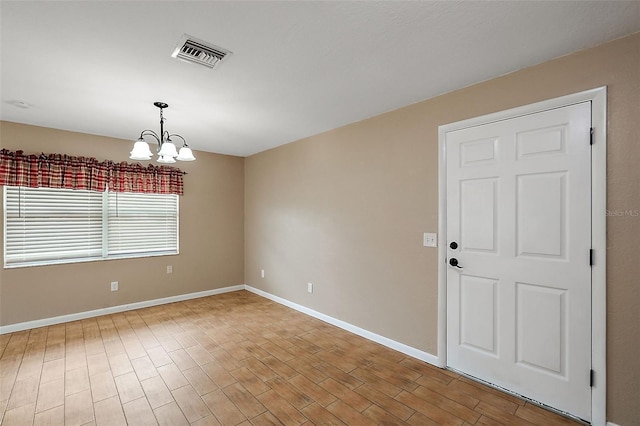 empty room with hardwood / wood-style floors and a notable chandelier