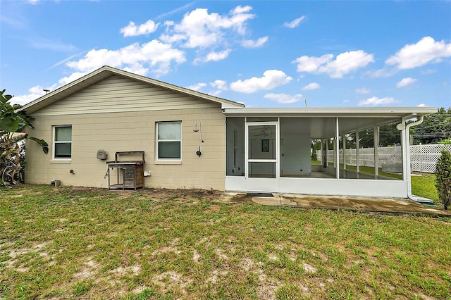 rear view of property with a sunroom and a lawn