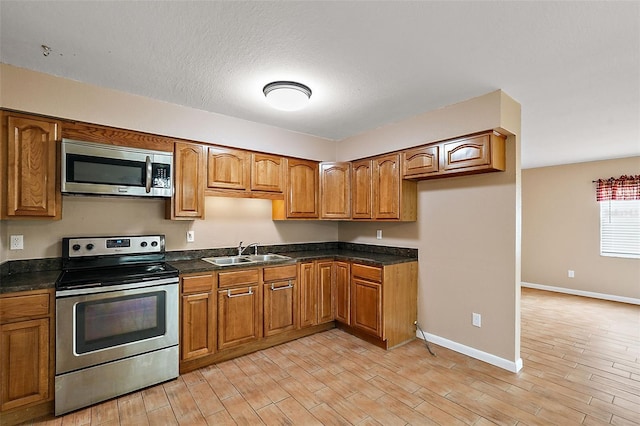 kitchen with sink, a textured ceiling, and appliances with stainless steel finishes