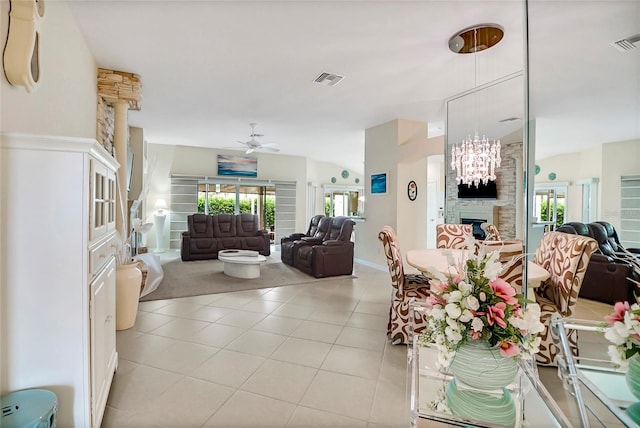 tiled living room with ceiling fan with notable chandelier and a large fireplace