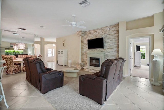 tiled living room with ceiling fan and a fireplace