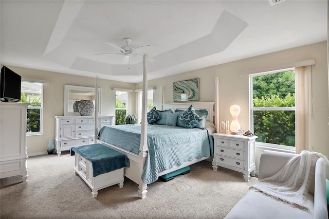 bedroom with ceiling fan, baseboards, a raised ceiling, and light colored carpet