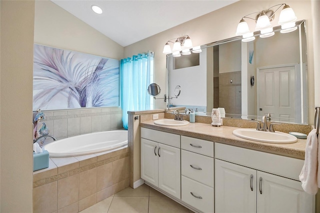 bathroom with tile patterned flooring, vanity, tiled bath, and vaulted ceiling