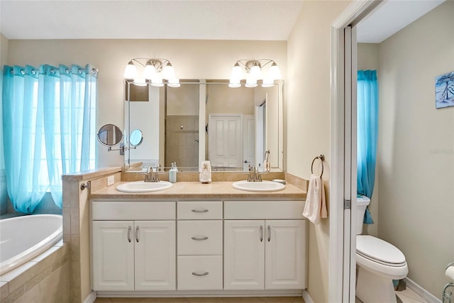 bathroom with double vanity, tiled tub, a sink, and toilet