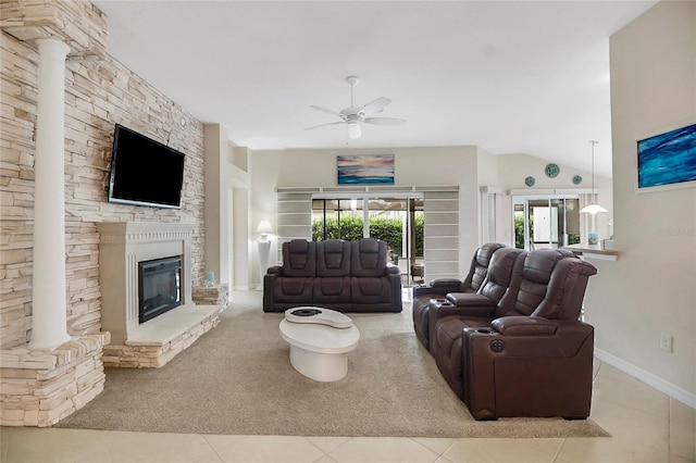 living room featuring a stone fireplace, ceiling fan, and light tile patterned flooring