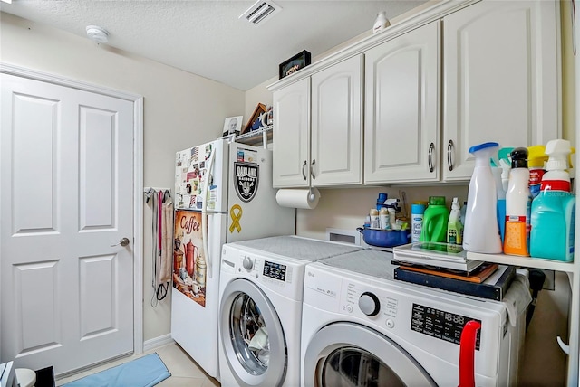 washroom with washer and dryer, light tile patterned flooring, cabinets, and a textured ceiling