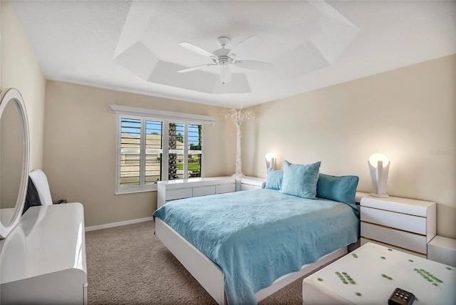 carpeted bedroom featuring a raised ceiling and ceiling fan