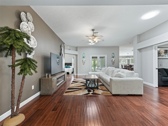 living room with dark wood-type flooring, ceiling fan, a textured ceiling, and french doors