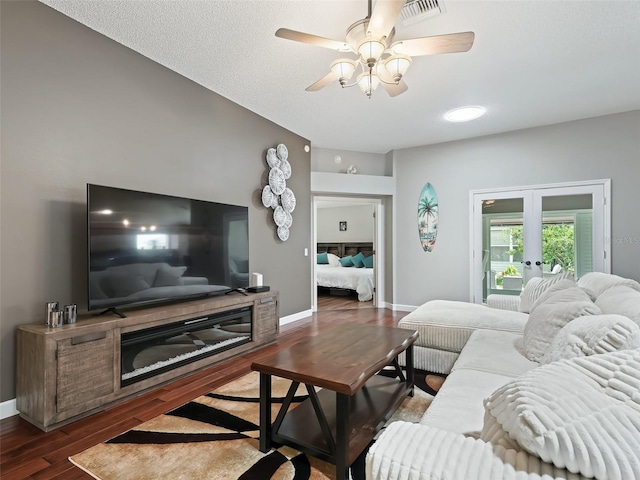 living room with french doors, ceiling fan, dark hardwood / wood-style flooring, and a textured ceiling