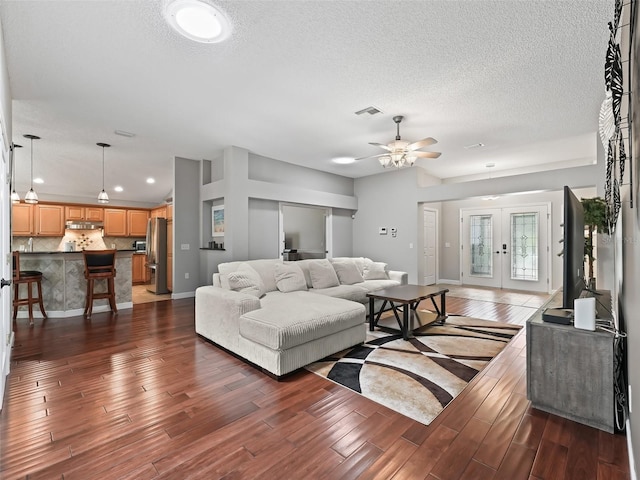 living room with a textured ceiling, ceiling fan, and dark hardwood / wood-style floors