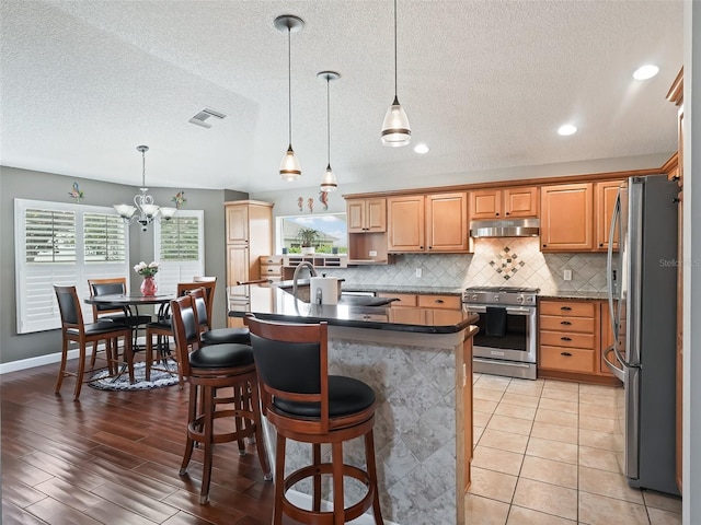 kitchen with a wealth of natural light, stainless steel appliances, decorative backsplash, and light hardwood / wood-style floors