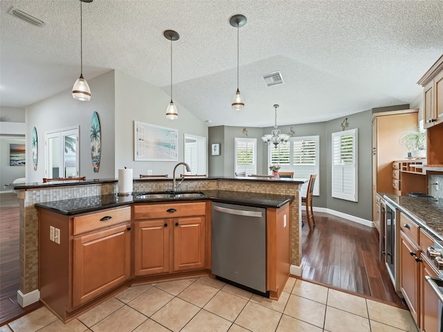 kitchen featuring dishwasher, light wood-type flooring, sink, an island with sink, and a textured ceiling